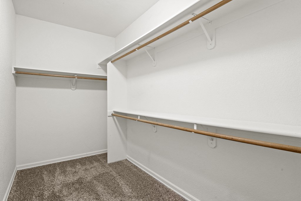 a spacious walk in closet with white walls and carpet