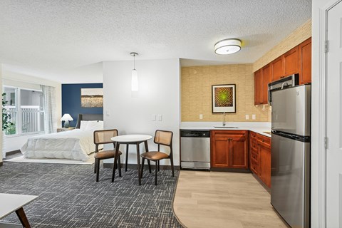 A kitchen with a refrigerator, table and chairs.