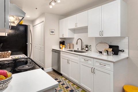 A kitchen with white cabinets and a black refrigerator.