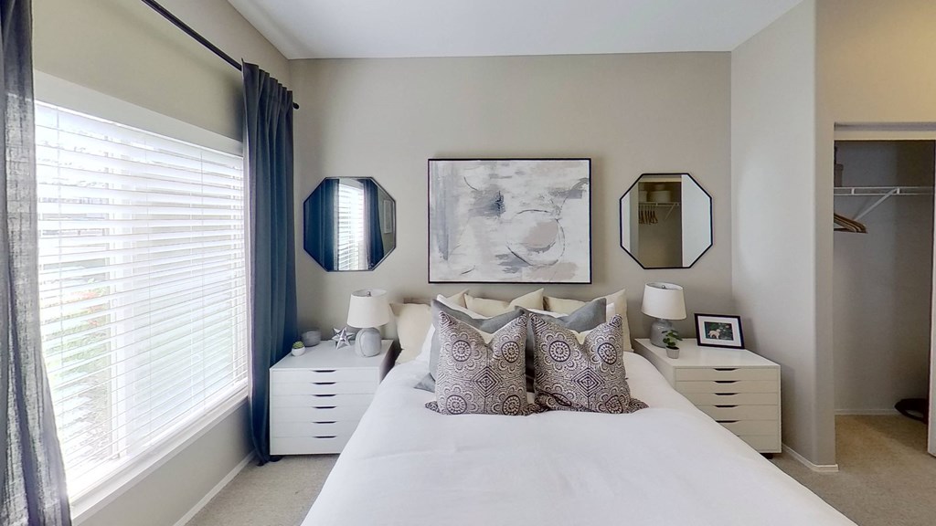 a bedroom with white bedding and two white chests of drawers