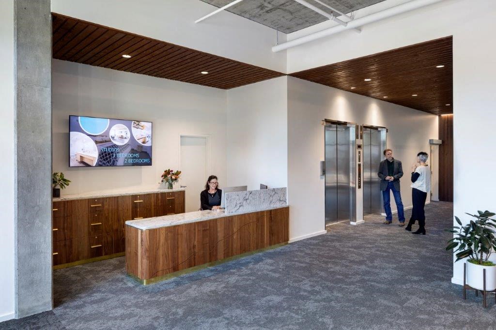 people standing in a lobby of a building with a reception desk