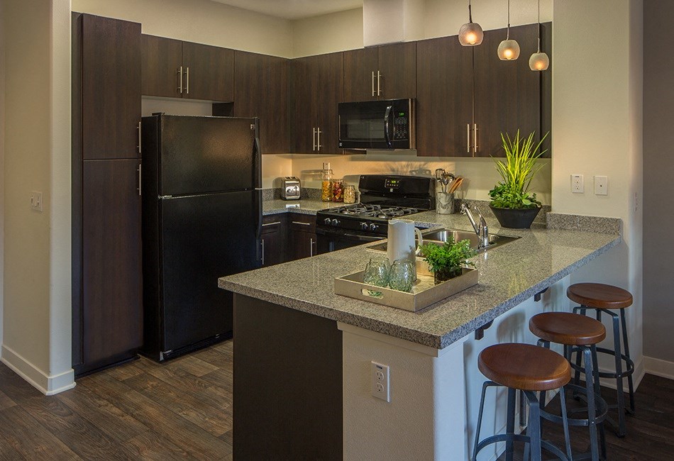 a kitchen with black appliances and a counter with stools