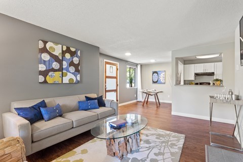 A living room with a couch, coffee table, and a painting on the wall.