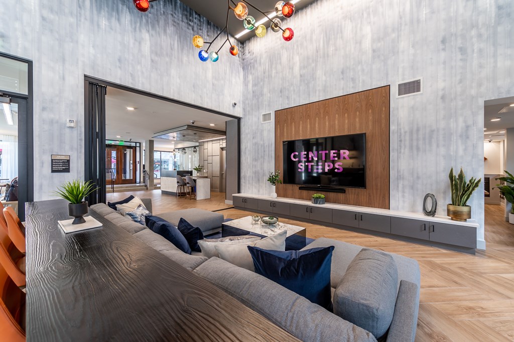 A modern living room with a grey couch and a wooden entertainment center.