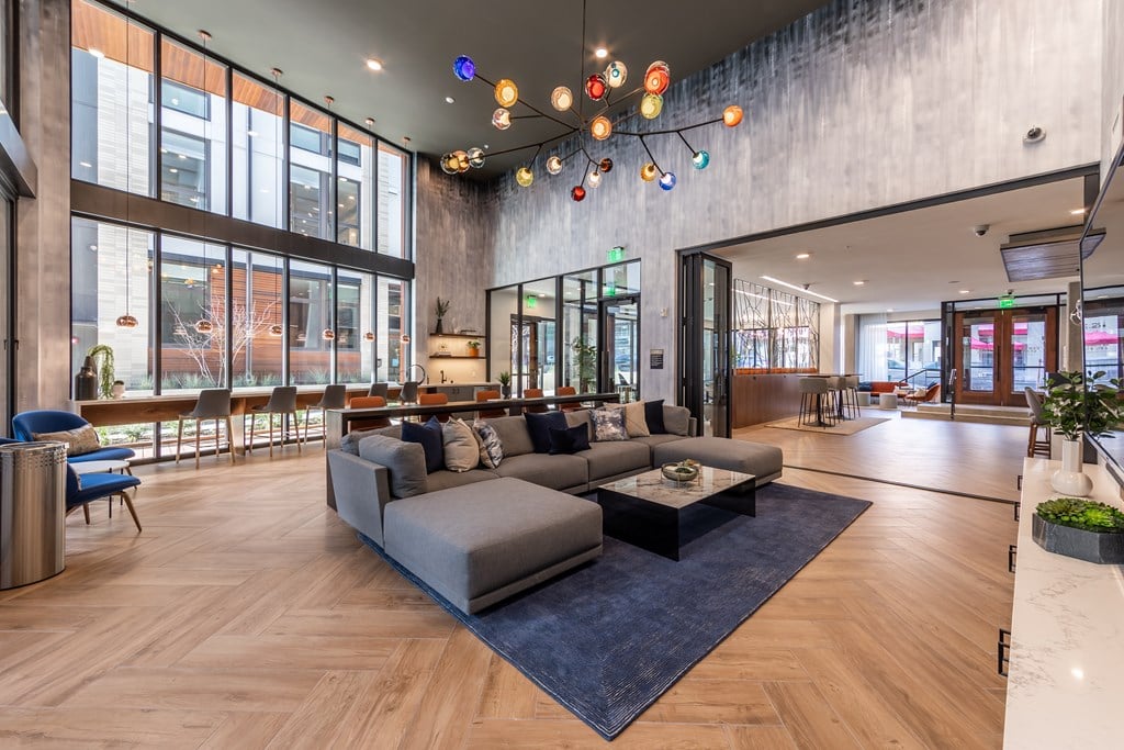 A modern living room with a grey sofa and a wooden floor.