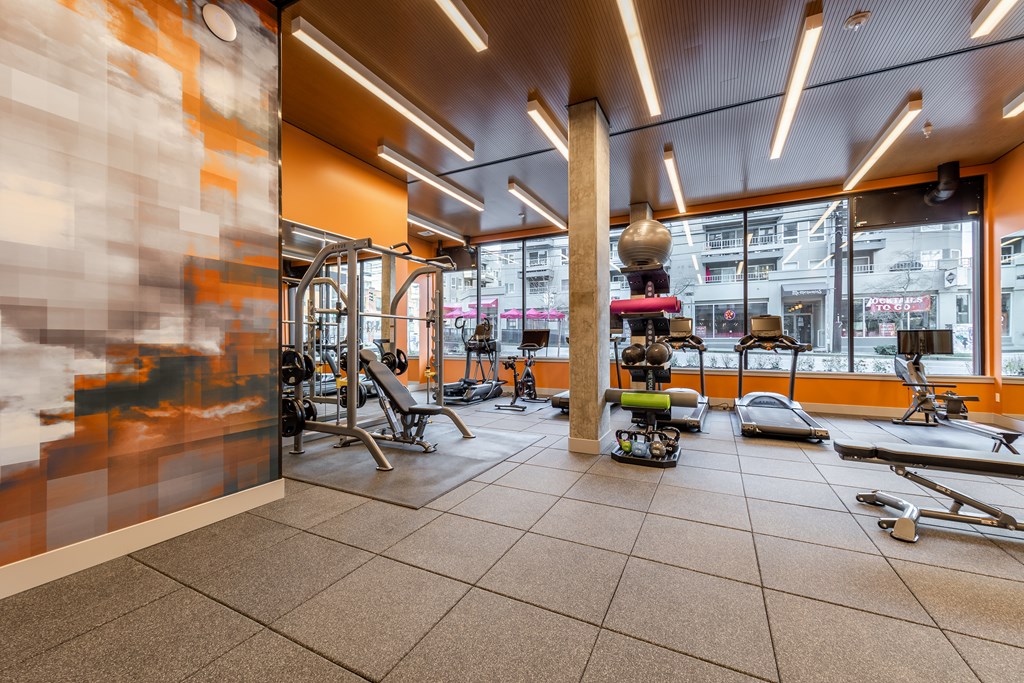 A gym with orange walls and a variety of equipment.