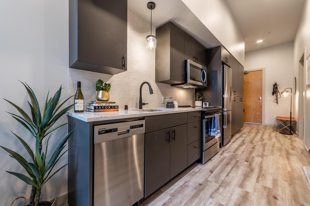A modern kitchen with stainless steel appliances and wooden flooring.