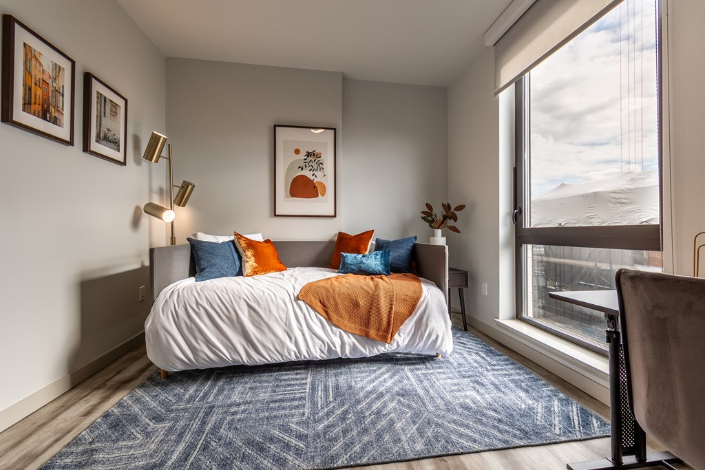 A bedroom with a bed, a chair, and pictures on the wall.