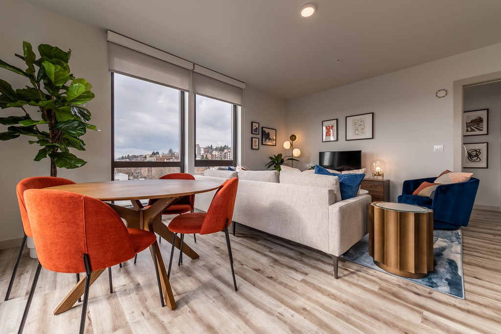 A living room with a white couch, orange chairs, and a wooden table.