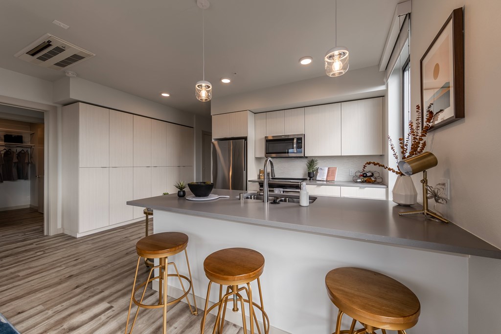 A modern kitchen with a bar area and stools.