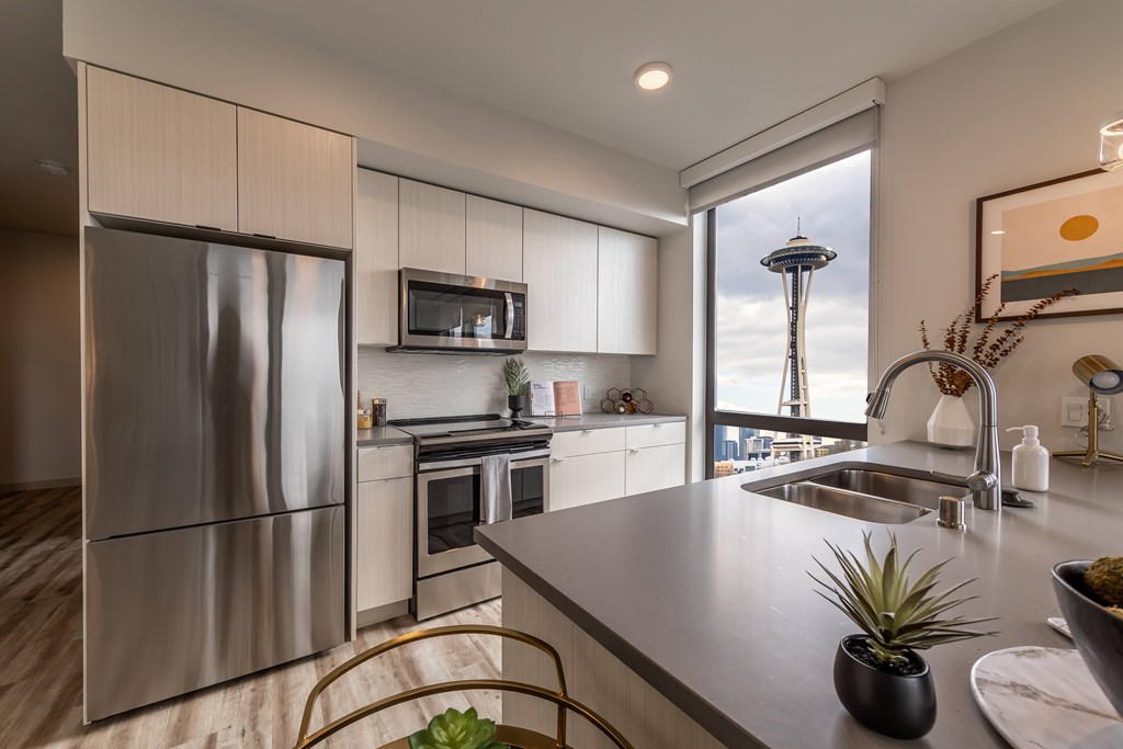 A modern kitchen with a stainless steel refrigerator and a view of the Seattle Space Needle.