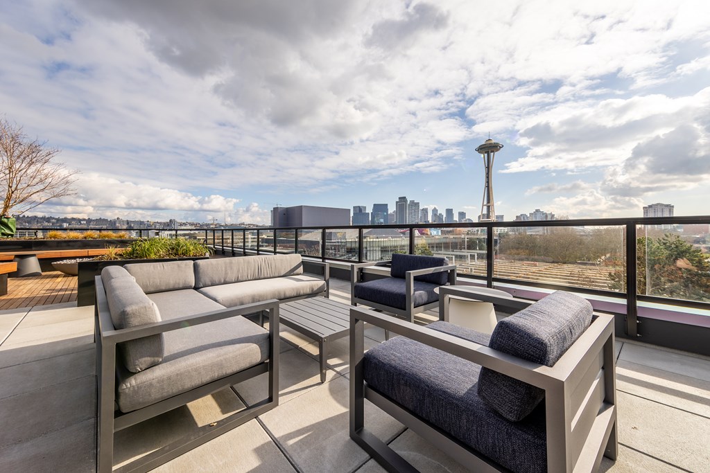 A patio with two couches and a table overlooking a city skyline.