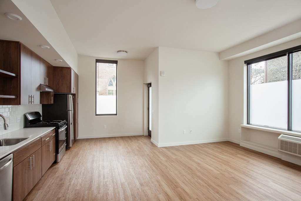 an empty living room and kitchen with wood flooring and a window