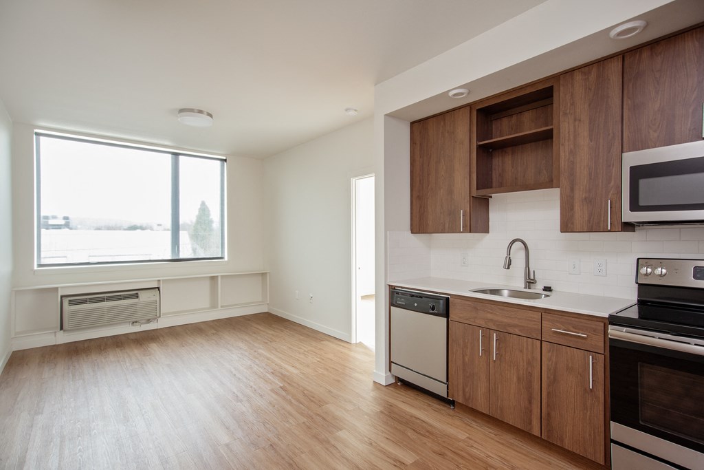 an empty kitchen with wood flooring and a window
