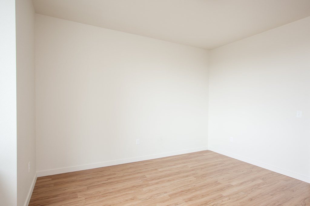 an empty room with wood floors and white walls