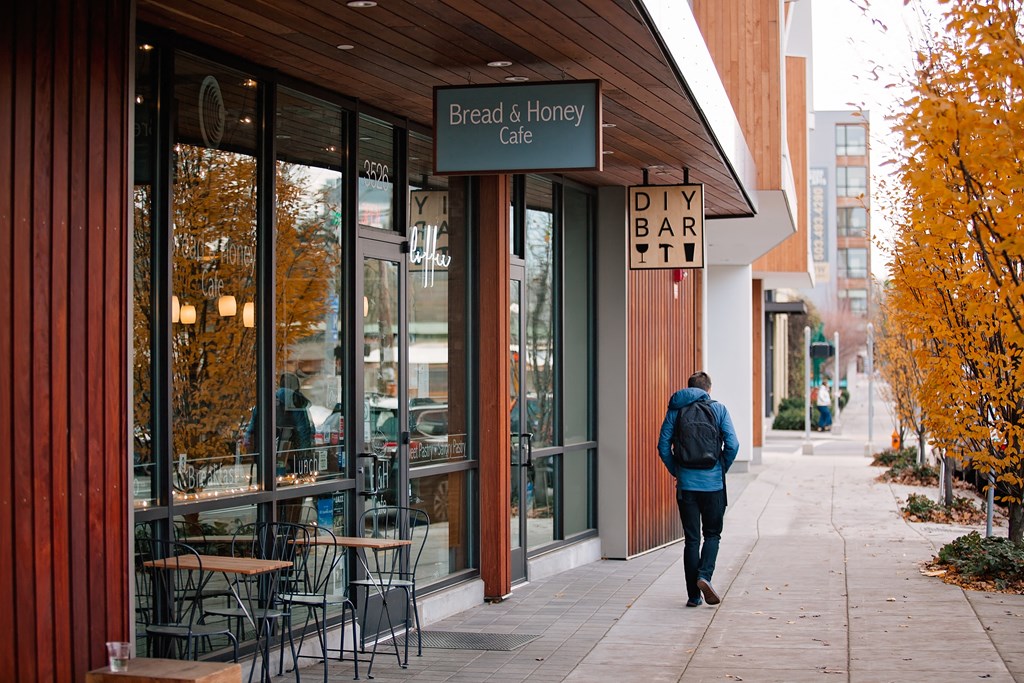 a man walking down a sidewalk in front of a bar