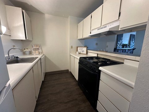 A small kitchen with white cabinets and a black stove.