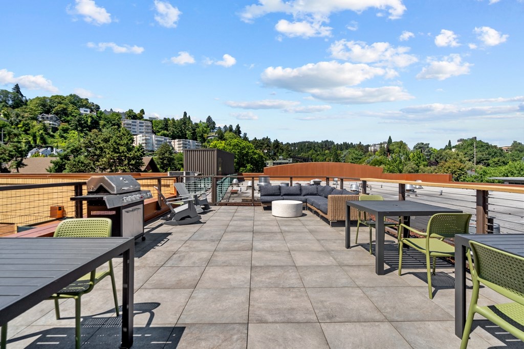 a rooftop patio with tables and chairs and a grill