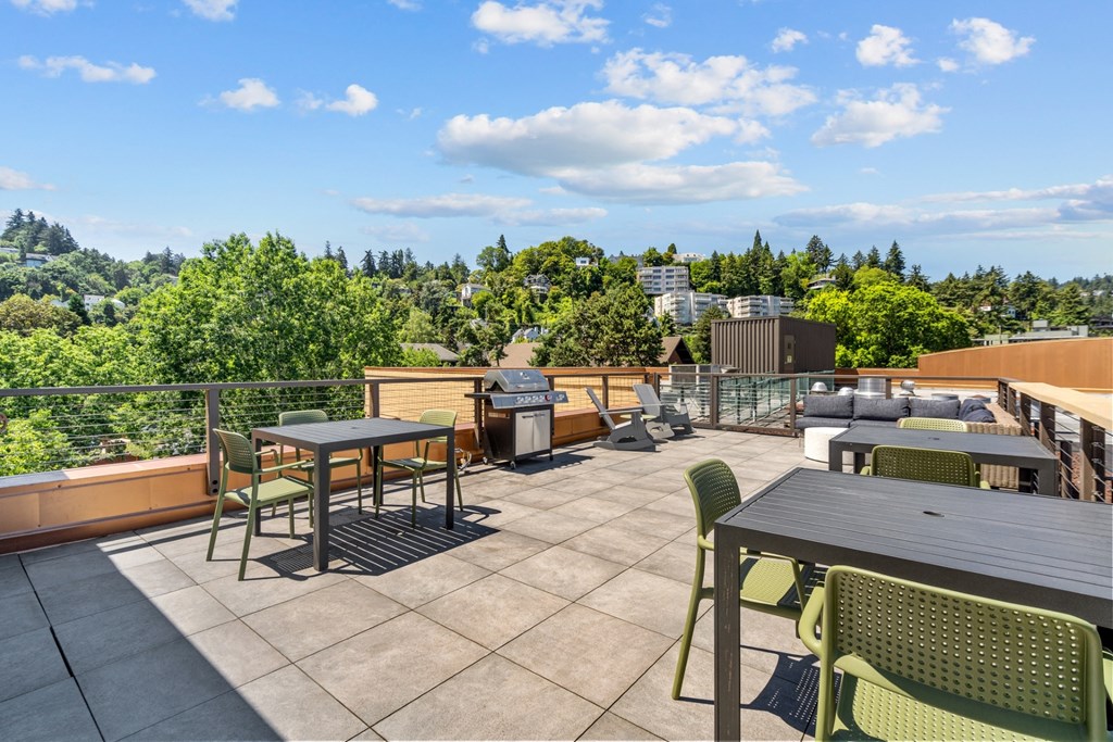 a rooftop patio with tables and chairs and a grill