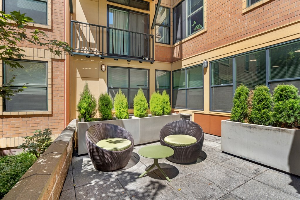 a patio with two chairs and a table in front of a building
