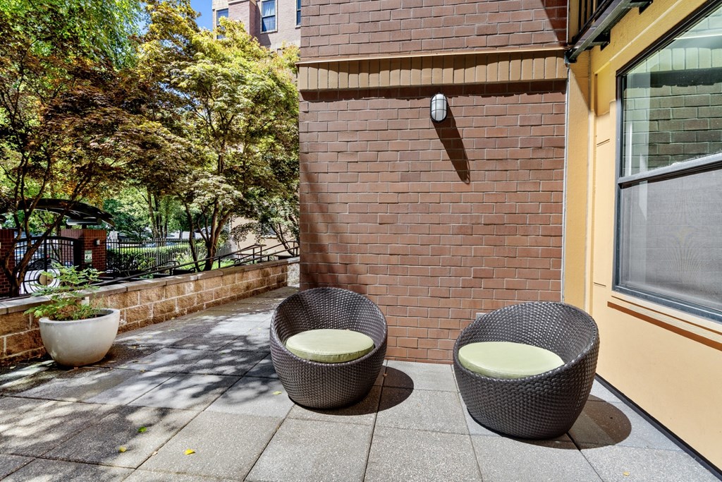 two chairs sit on a patio in front of a brick wall