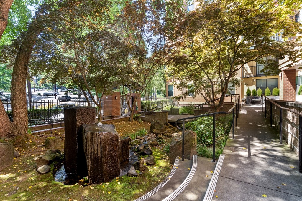 a park with a creek and trees in front of a building