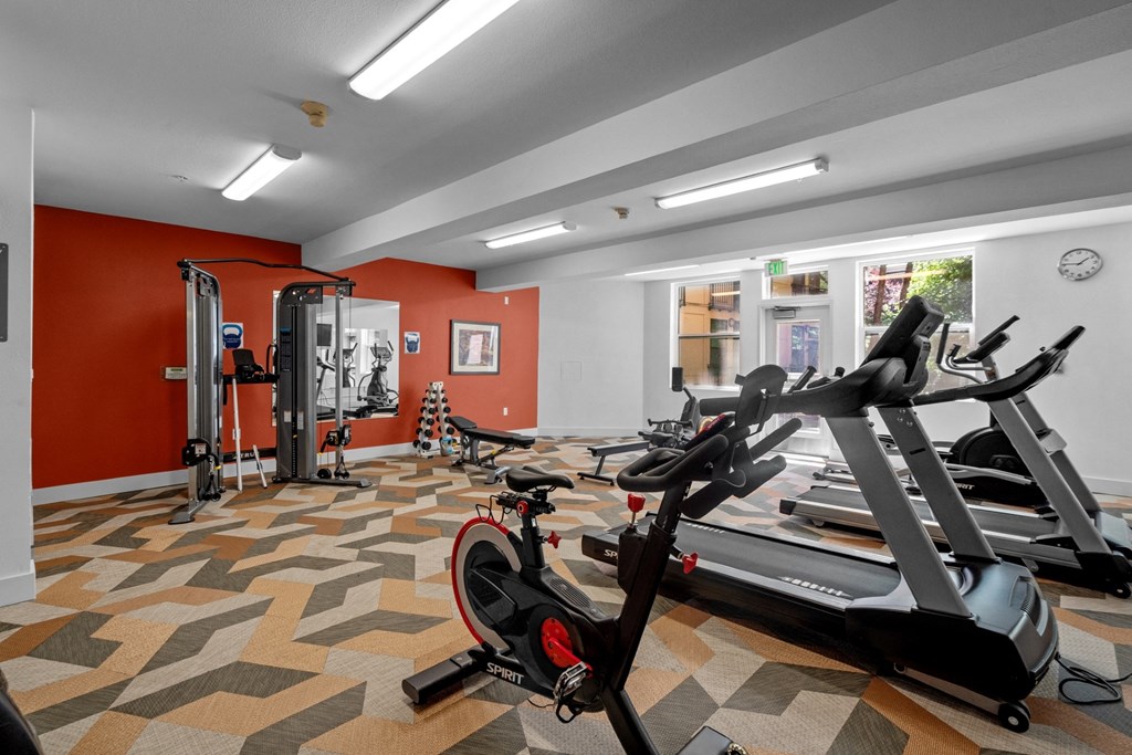a gym with treadmills and other exercise equipment in a room with red walls