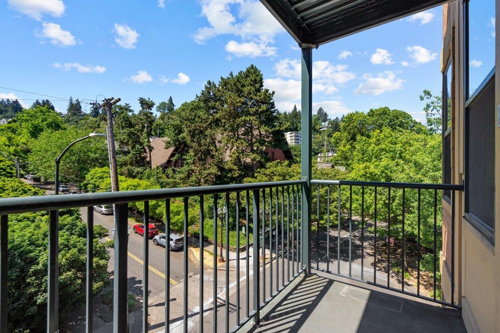 a balcony with a view of a parking lot and trees