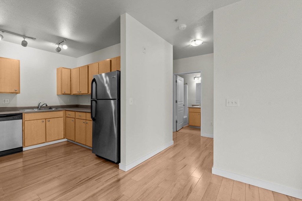a kitchen with wood flooring and a black refrigerator