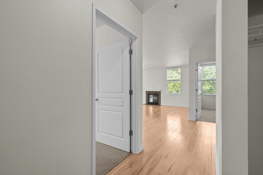 a spacious living room with a white door and a hardwood floor