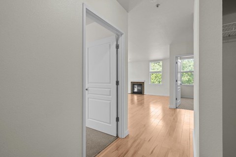 Hallway view into living room with white walls and wood-style flooring at Collins Circle apartments in the Goose Hollow district in Portland, Oregon.