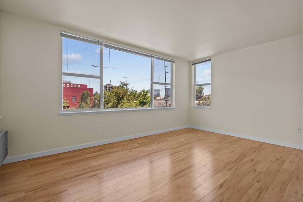an empty living room with wood floors and large windows