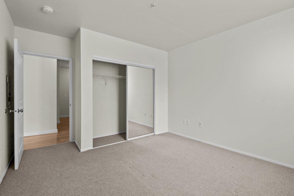 an empty bedroom with closet doors and carpet