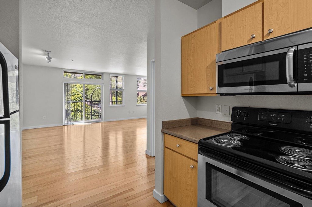 an empty kitchen and living room with wood flooring and appliances