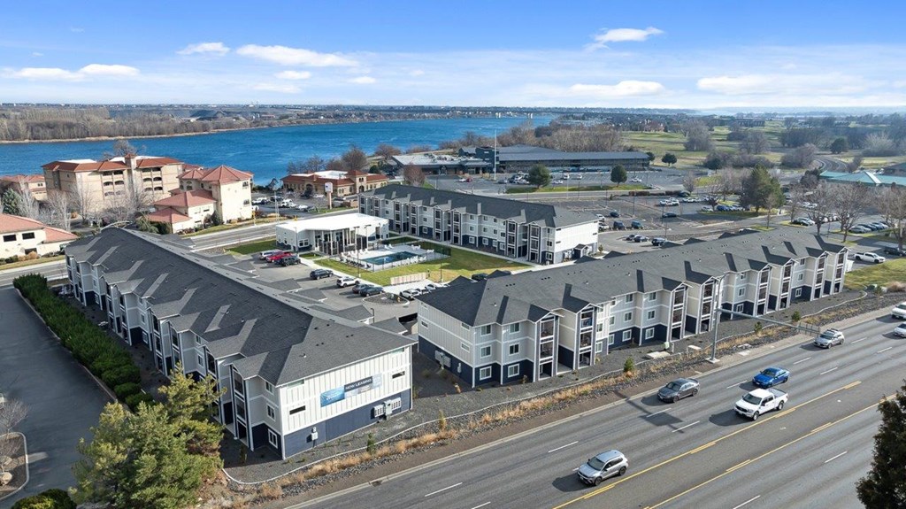 A large building complex is situated next to a busy highway.
