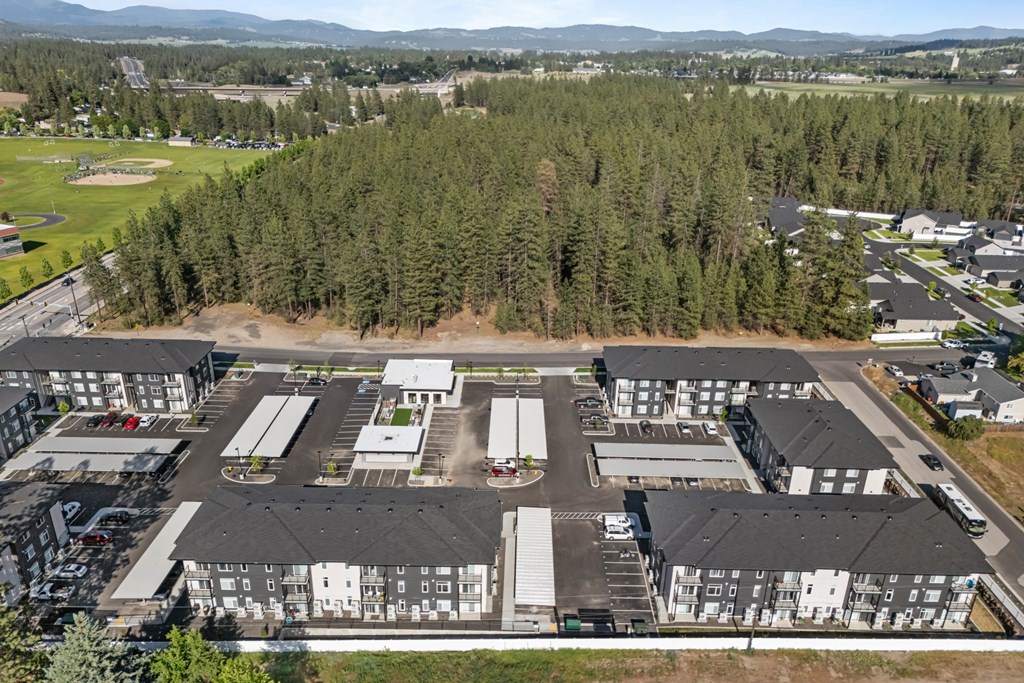 A large building complex surrounded by trees and a parking lot.