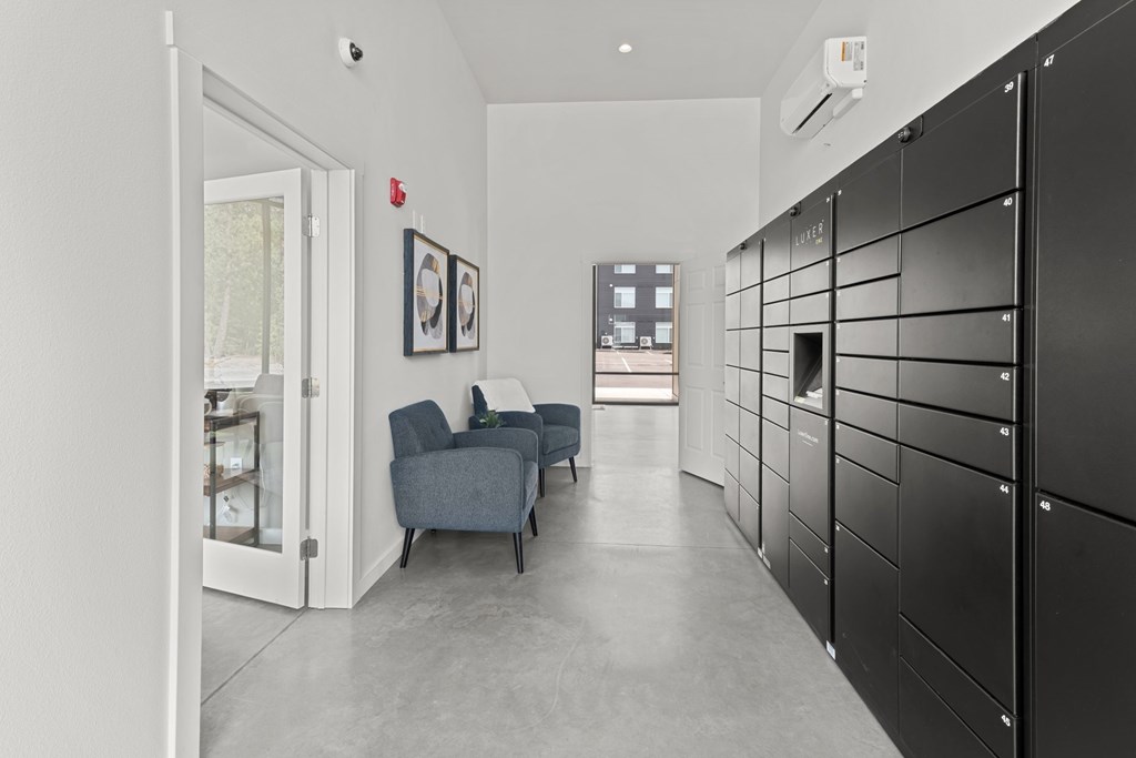 A hallway with black lockers on the right and a blue couch in the middle.