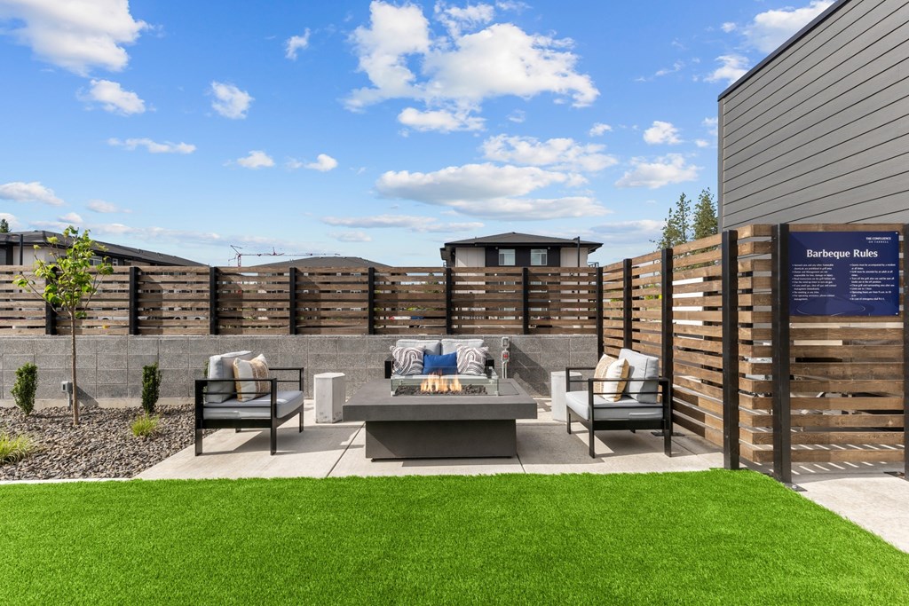 A backyard with a wooden fence and a barbeque grill.