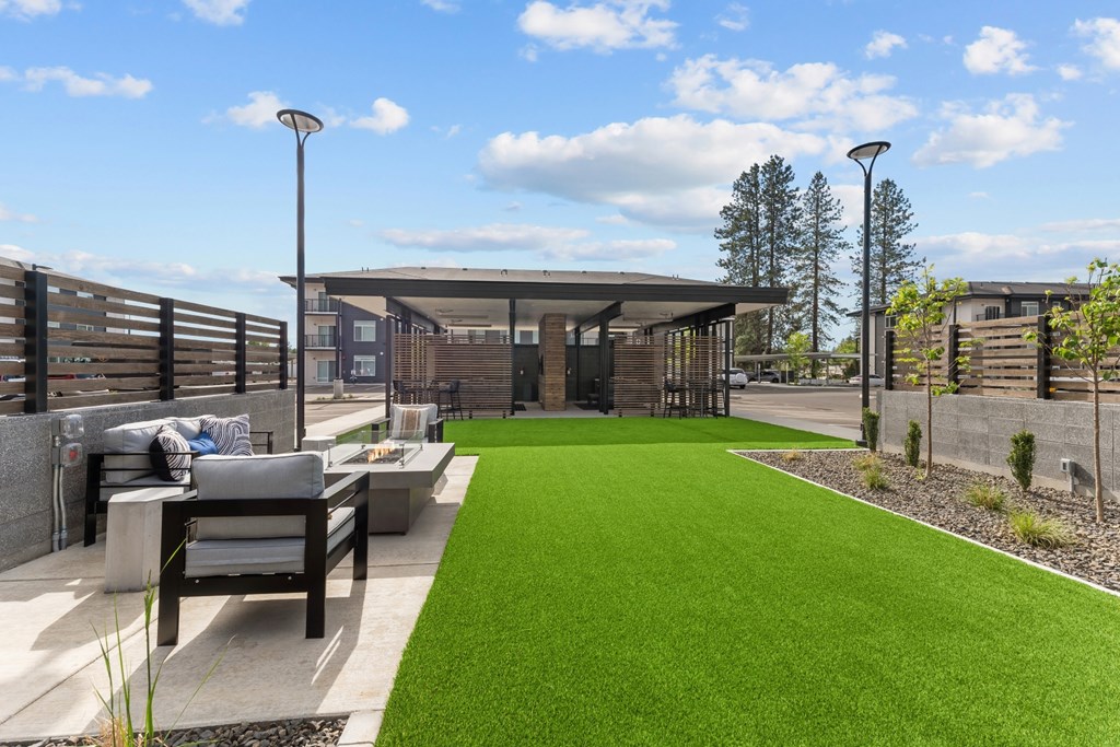 A modern outdoor seating area with a green lawn and a concrete bench.