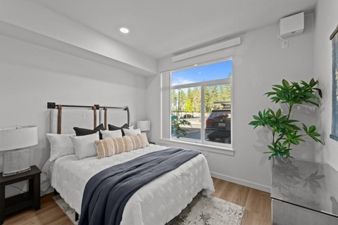 Modern bedroom with white bedding and large window at Confluence on Farwell Apartments, Spokane, WA 99218