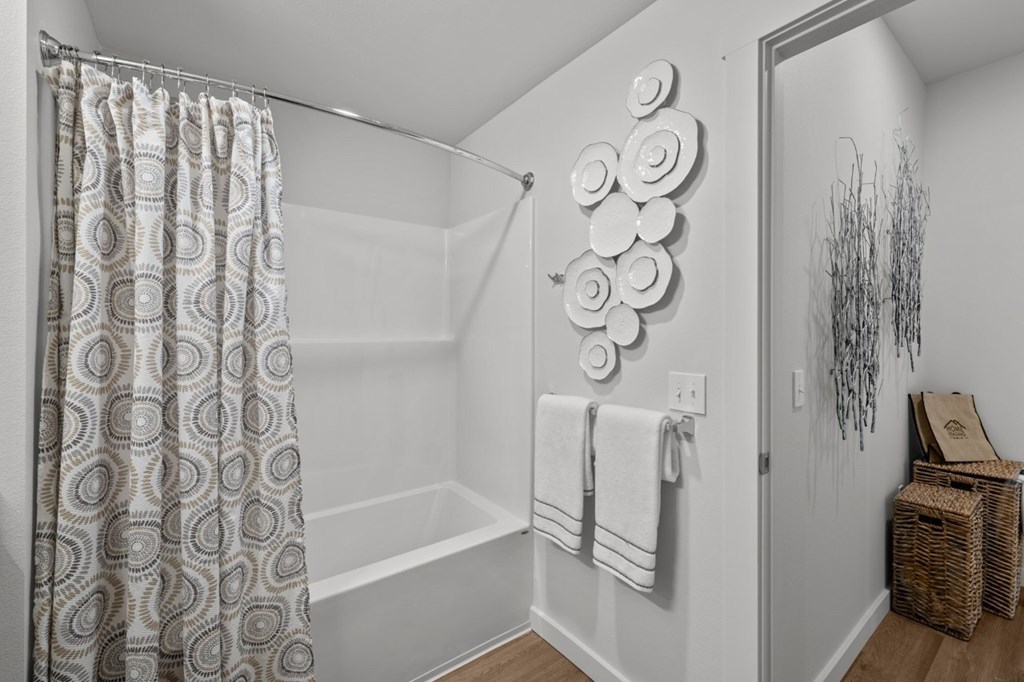 A bathroom with a shower, towel rack, and a decorative wall piece.