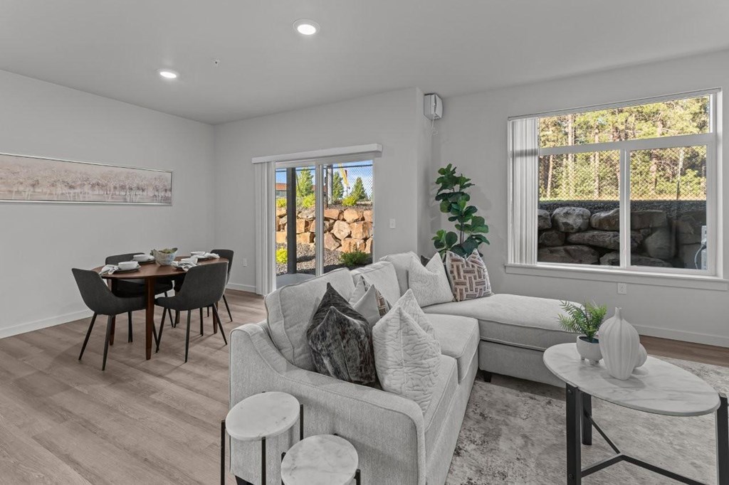 A living room with a grey couch, a black table, and a painting on the wall.