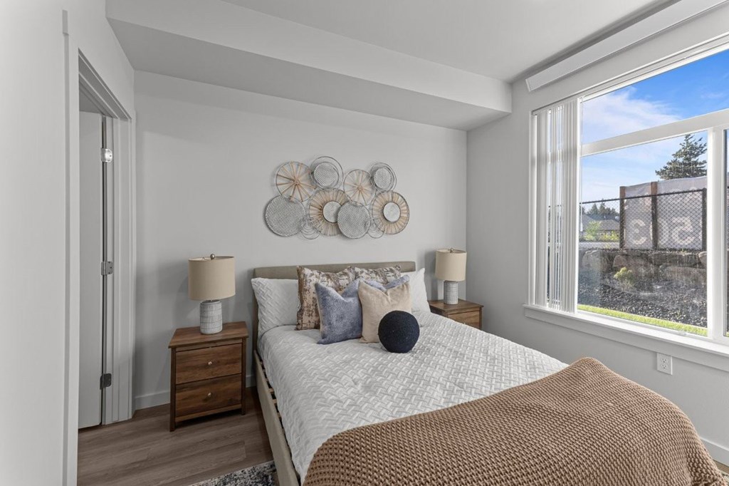 A bedroom with a large bed, a wooden nightstand, and a window overlooking a stone wall.