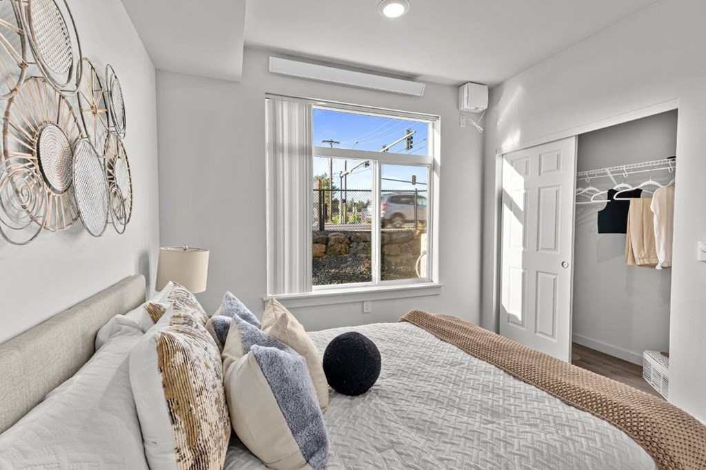 A bedroom with a large bed and a window overlooking a street.