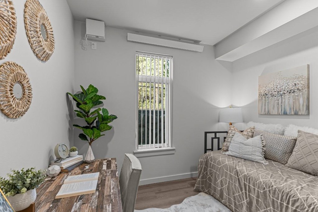A living room with a couch, a table, a window, and a painting on the wall.