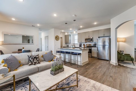 A modern kitchen with a breakfast bar and a living room with a sofa.
