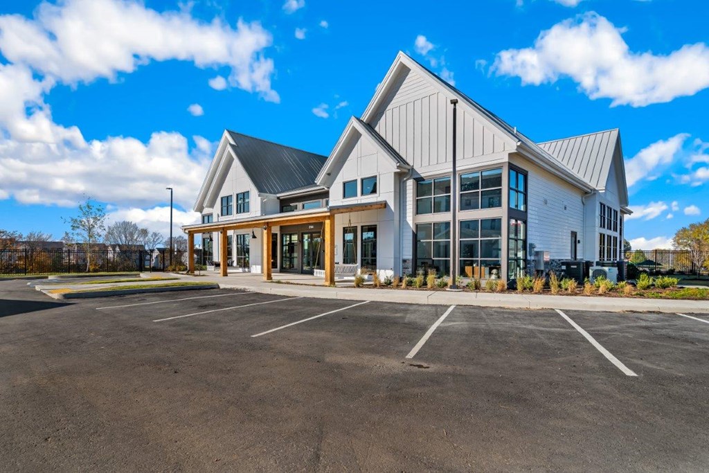 A large white building with a black roof and a parking lot in front.