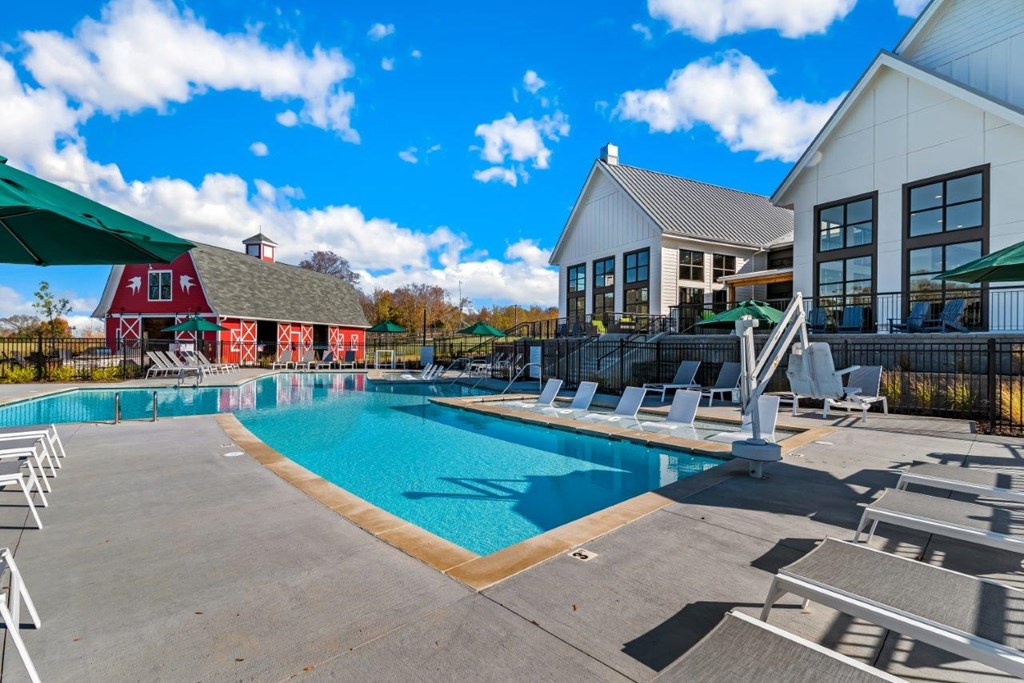A large swimming pool with lounge chairs and a white building in the background.