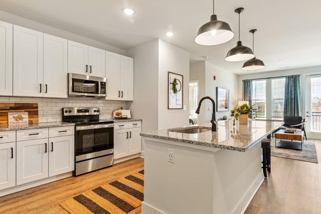 A kitchen with white cabinets and a granite countertop.
