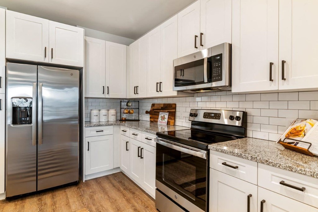 A kitchen with white cabinets and a stainless steel refrigerator.